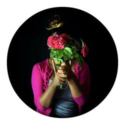 Midsection of woman holding umbrella while standing against black background