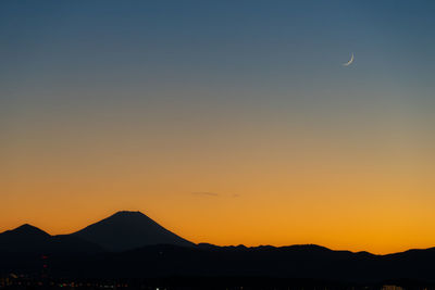 Scenic view of silhouette mountains against orange sky