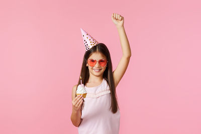 Portrait of young woman wearing sunglasses against pink background