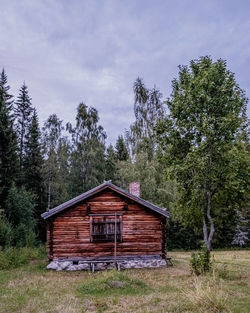 House amidst trees on field against sky