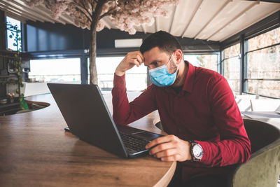 Worried man with mask looking for job online