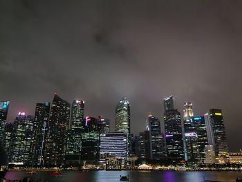 Illuminated modern buildings in city against sky at night
