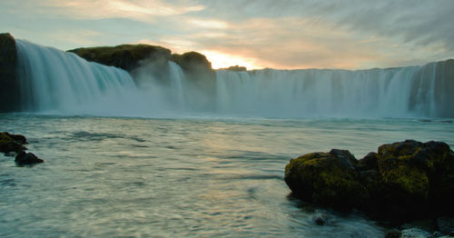 Scenic view of waterfall at sunset