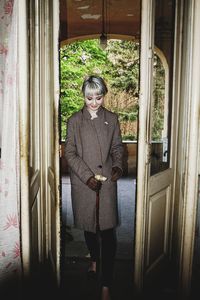 Portrait of smiling woman standing against door