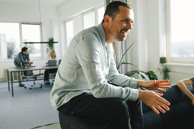 Side view of smiling male businessman discussing at office