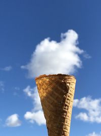 Low angle view of ice cream cone by cloud sky