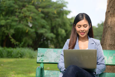 Young woman looking away while sitting on mobile phone