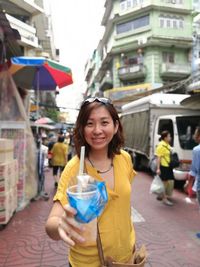 Portrait of smiling woman standing at market in city