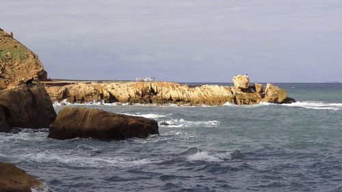 Rocks on sea shore against the sky