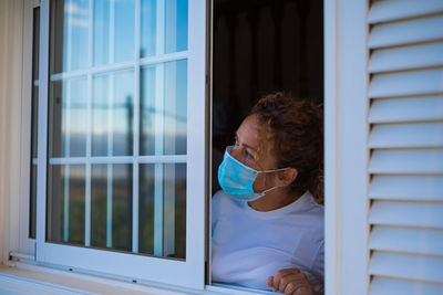 Portrait of woman looking through window in building