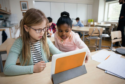 Serious students looking at digital tablet while sitting in classroom