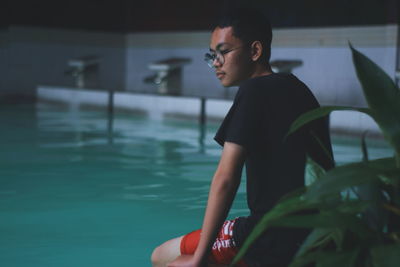 Young man sitting at poolside