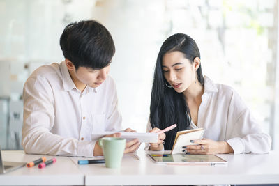 Young colleagues discussing at desk in office