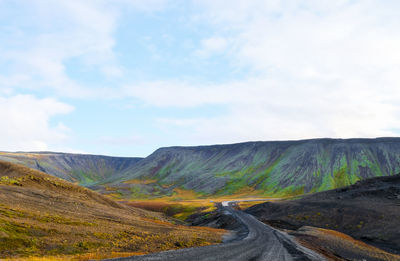 Road leading towards mountains against sky