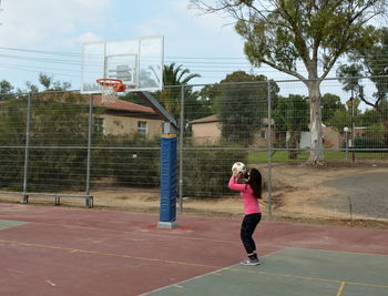 Man playing with basketball hoop against sky