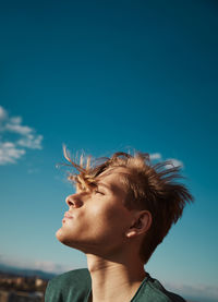 Cute young blond male looking up the sky on sunny day