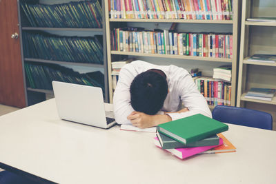 Male student with head on table in library