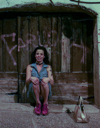 Portrait of young woman standing against old building