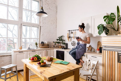 Young and beautiful housewife woman cooking in a white kitchen