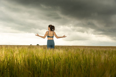 Woman standing amidst field against sky