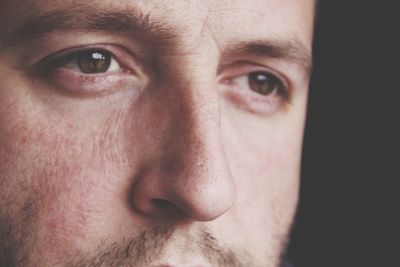 Close-up of serious man looking away against black background