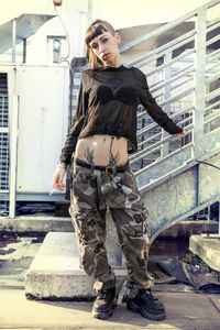 Portrait of young woman standing against steps in city