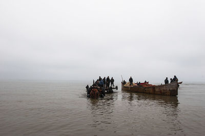 Group of people on boat in sea against sky