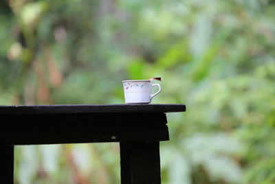 Close-up of coffee cup on railing