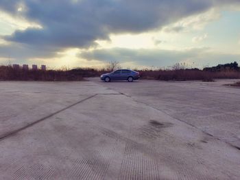 Cars on road against cloudy sky