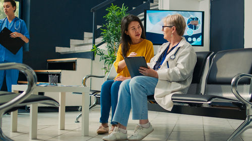 Full length of young woman using laptop while sitting at airport