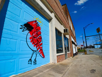 Low angle view of red umbrella on building against blue sky