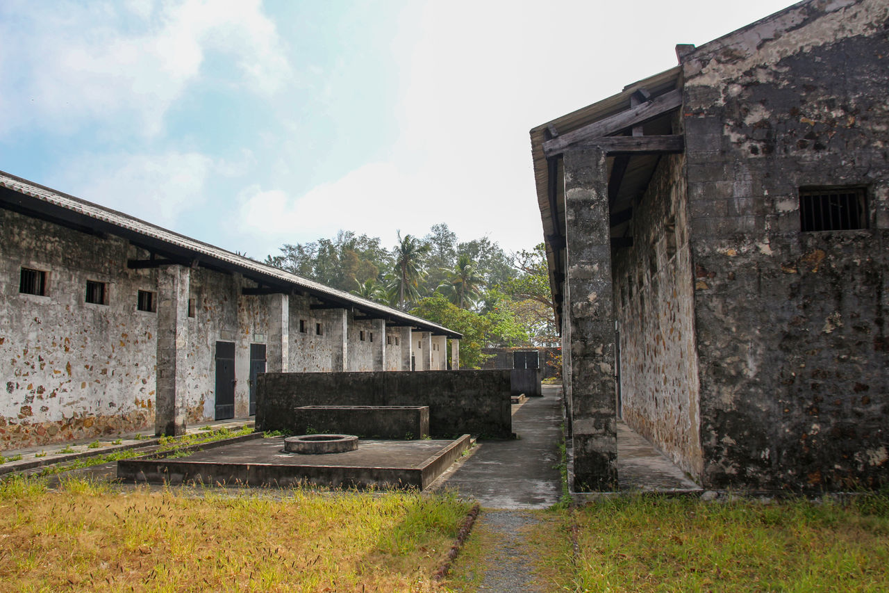 EXTERIOR OF OLD BUILDING BY HOUSE AGAINST SKY