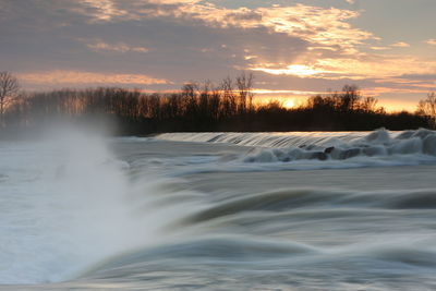 Scenic view of waterfall against sky at sunset