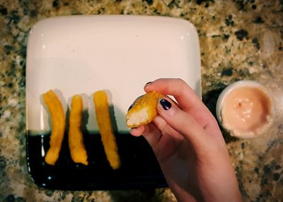 Cropped hand of woman having food at table