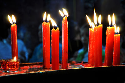 Unidentified believers praying and burning candles for the gods in a pagoda.