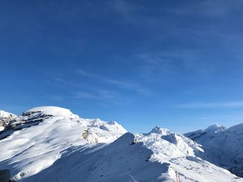 Scenic view of snowcapped mountains against blue sky