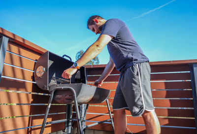 Low angle view of men on railing against blue sky