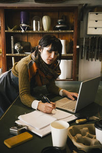 Female entrepreneur working on laptop in upcycling store