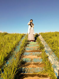 Woman standing on field against clear sky