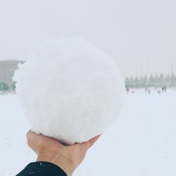 Close-up of hand holding snow covered against sky