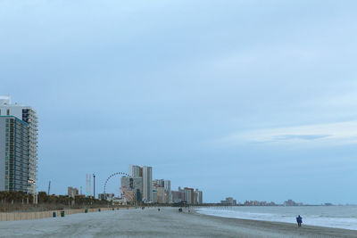 Scenic view of beach by buildings against sky