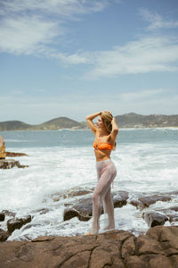 Rear view of woman standing at beach against sky