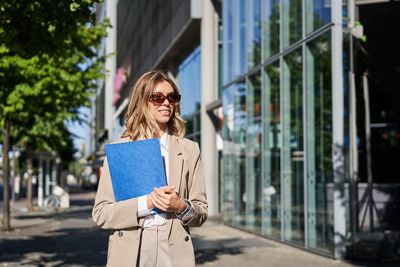 Young woman using mobile phone while standing in city