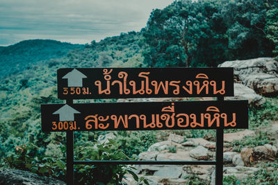 Information sign by trees against sky