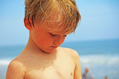 Close-up of shirtless boy at beach on sunny day