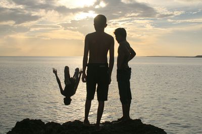 Silhouette people on beach against sky during sunset