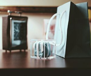 Close-up of gift box by paper bag on table