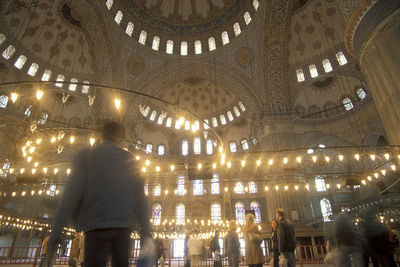 Rear view of people walking in illuminated building