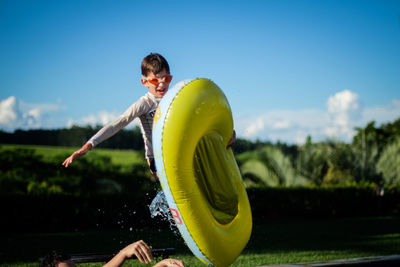 Boy jumping with inflatable raft in water park