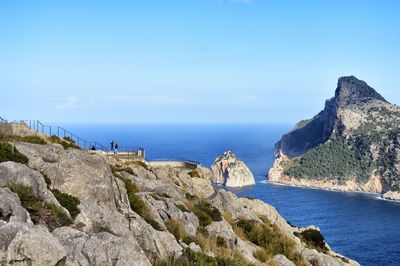 Scenic view of sea and rocks against blue sky